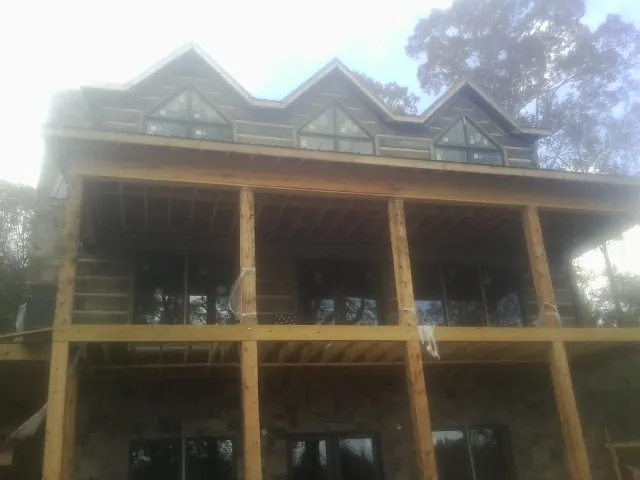 Dormers and porch framing on a large log home under construction — Roof Coating work by our crew in Kings Mountain
