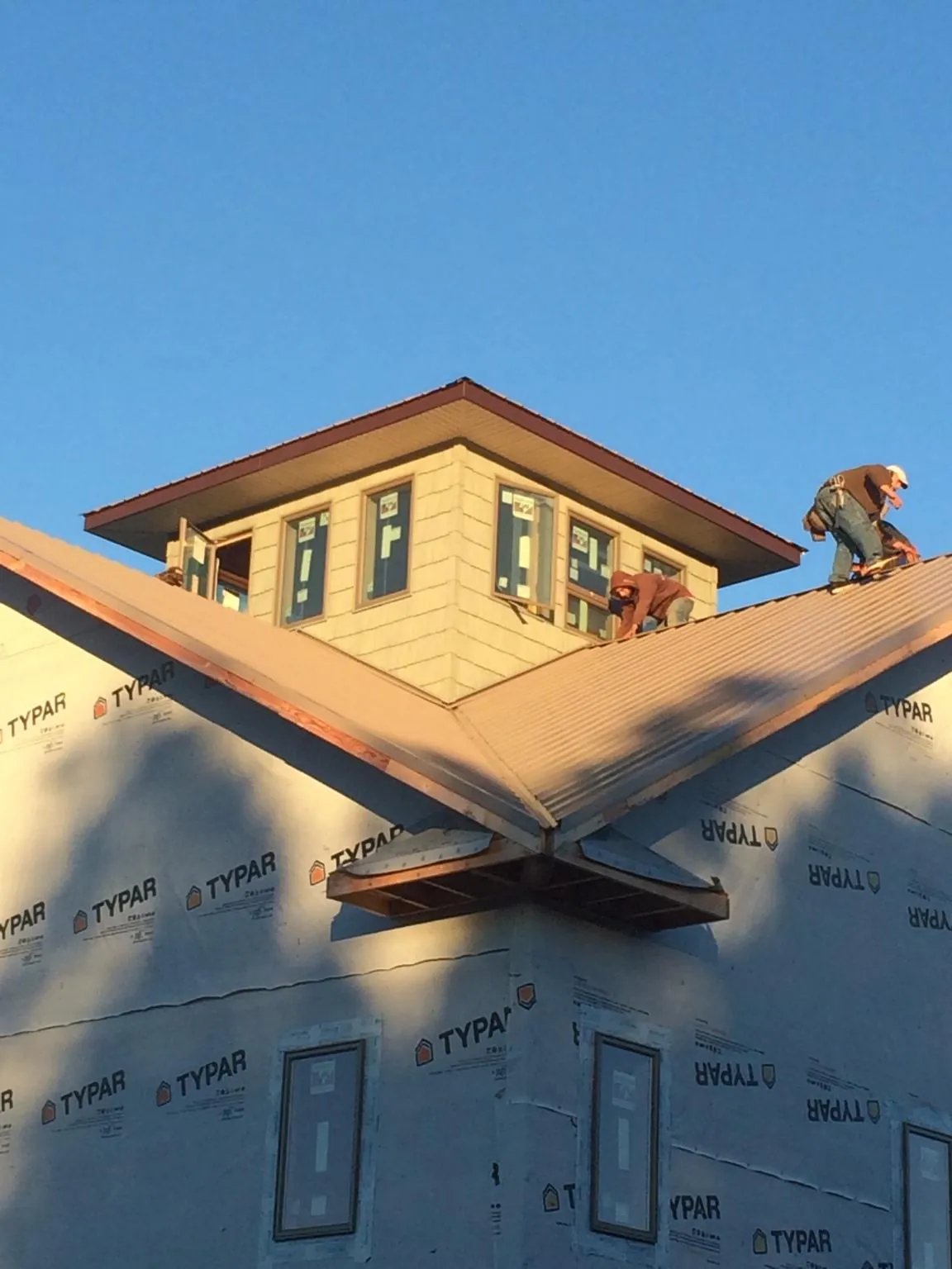 Roofers working around a rooftop cupola on a new metal roof at sunset — Roof Waterproofing in Kings Mountain by Roofing Brothers